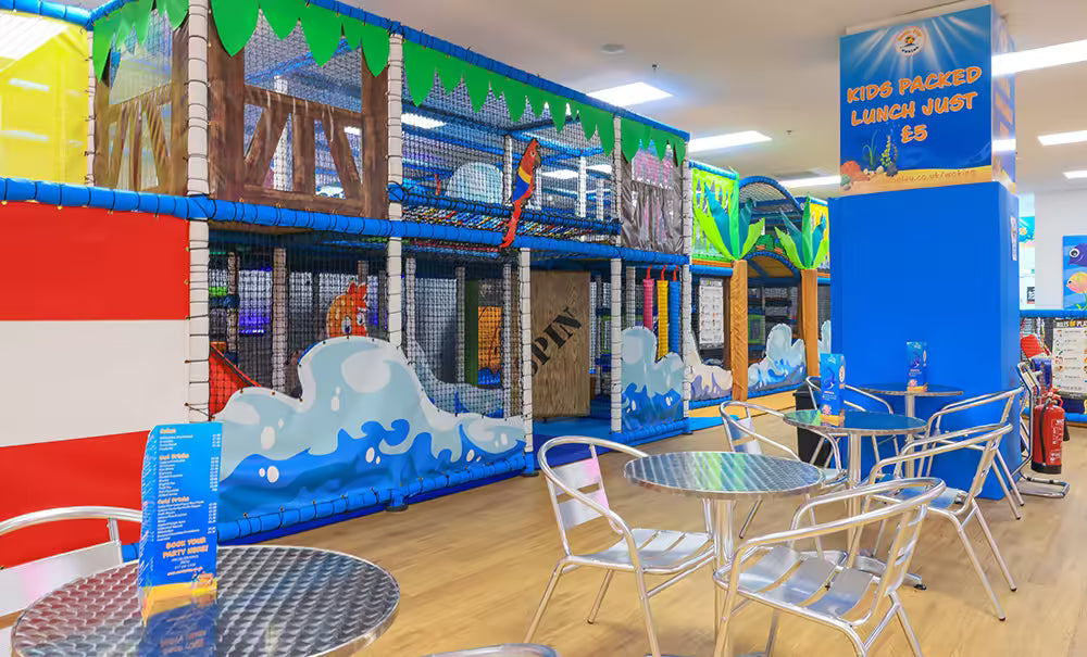 Children's play area with colorful walls and tables with chairs in a restaurant setting.